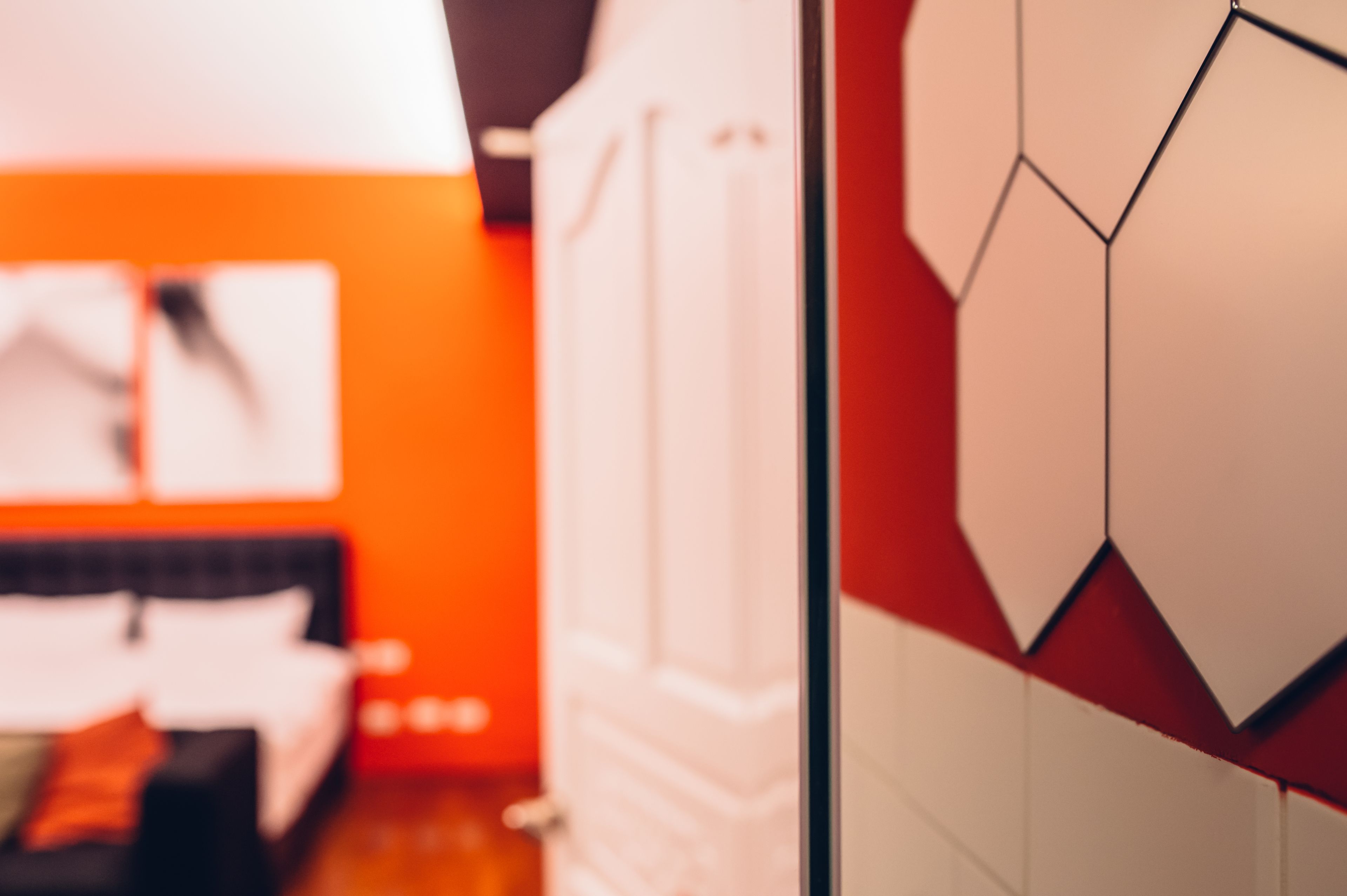 Una habitación con una cama, una pared blanca y un adorno geométrico en la pared.