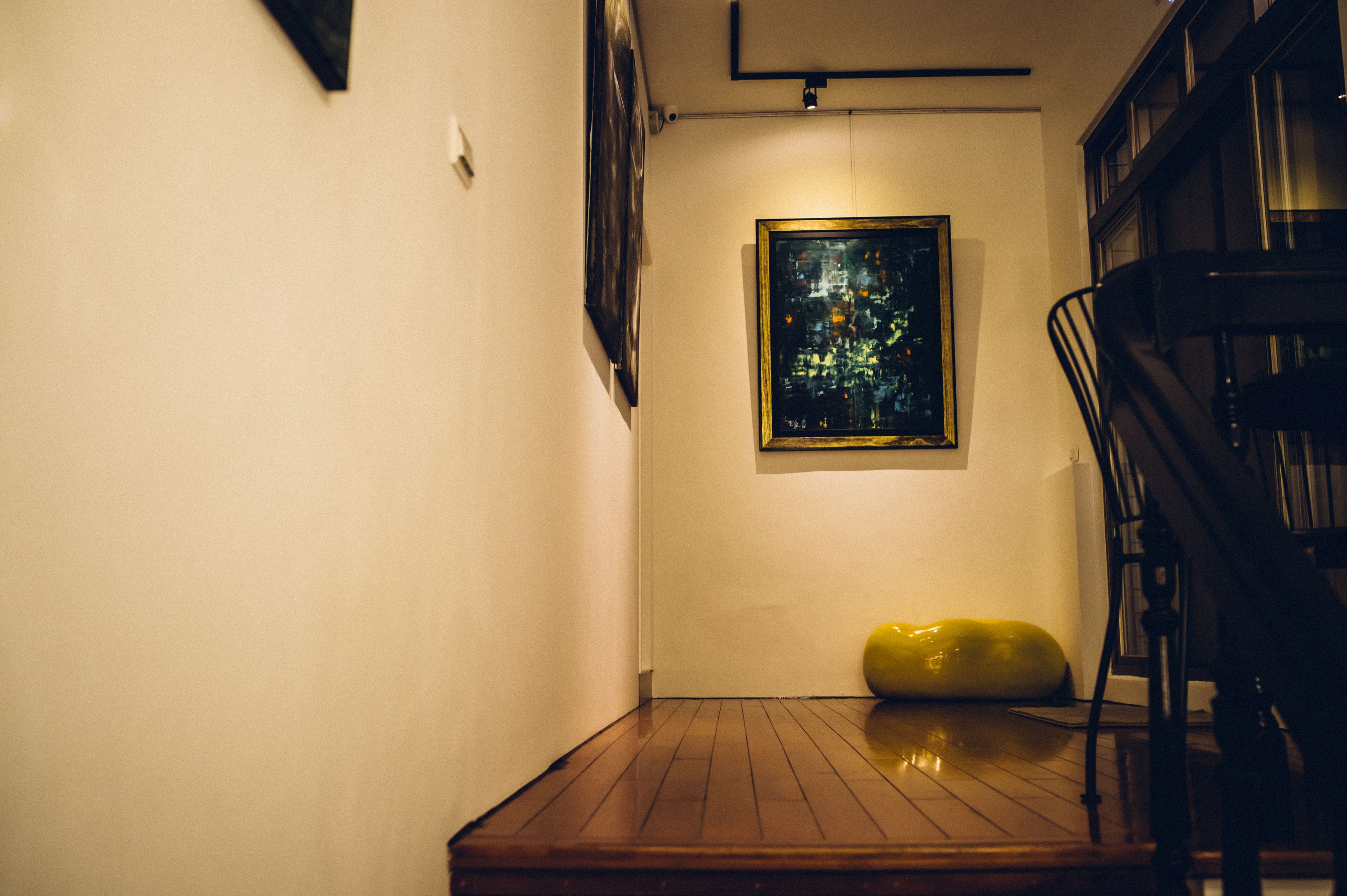 A hallway with a wooden floor, a staircase, and a painting on the wall.