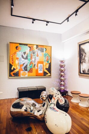 Una galería de arte moderno con pinturas abstractas, una escultura y mobiliario único.