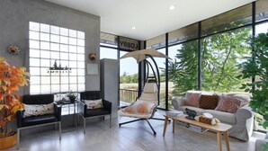 Una sala de estar moderna con un sofá, sillones, una silla colgante y una mesa de centro.