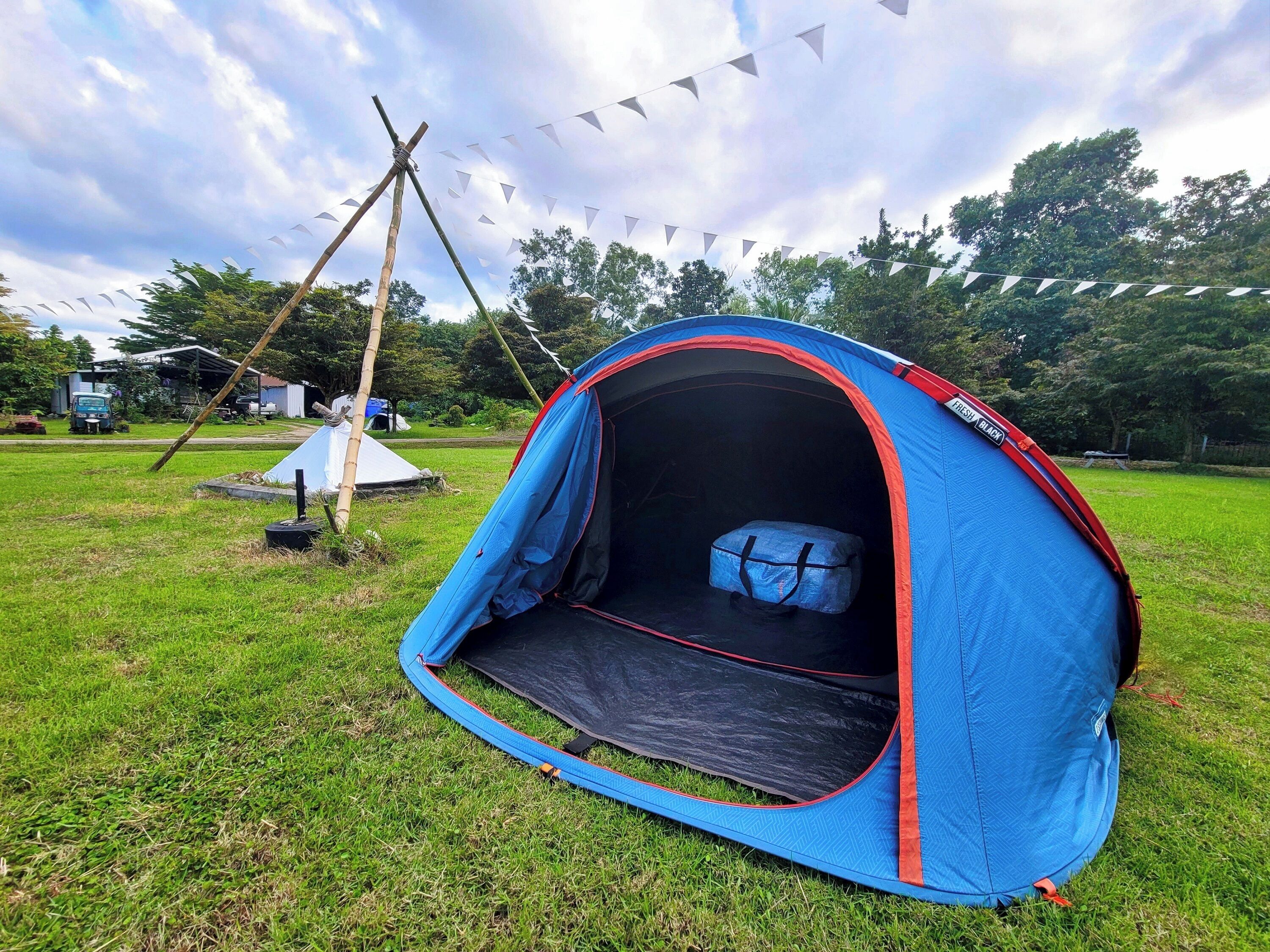 Una carpa azul con detalles rojos y un saco de dormir en su interior.