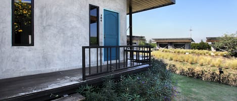 Un edificio con puerta azul, un balcón con barandilla negra y una terraza de madera.
