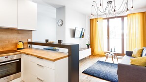 Una cocina moderna con encimera de madera, horno empotrado y comedor con mesa y sillas.
