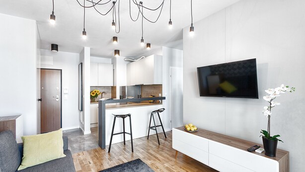 Una cocina moderna con una isla central, taburetes de bar y un televisor fijado a la pared.