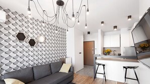 Una cocina moderna con una isla central, un sofá gris y una pared con estampado geométrico.