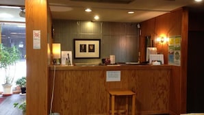 Un comptoir d’accueil avec un revêtement en bois, un tableau encadré au-dessus et un petit tabouret devant.