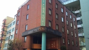Un immeuble en briques de plusieurs étages, sur lequel on peut lire l’inscription « Nagano Plaza Hotel ».