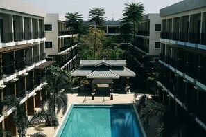 A hotel with a central swimming pool, multiple balconies, and a covered outdoor area.