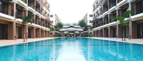 Una piscina rodeada de edificios de varios pisos con balcones y zonas de estar al aire libre.