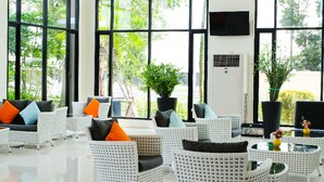 A spacious lobby with wicker furniture, large windows, and indoor plants. - Summer Tree Hotel (Bangkok)