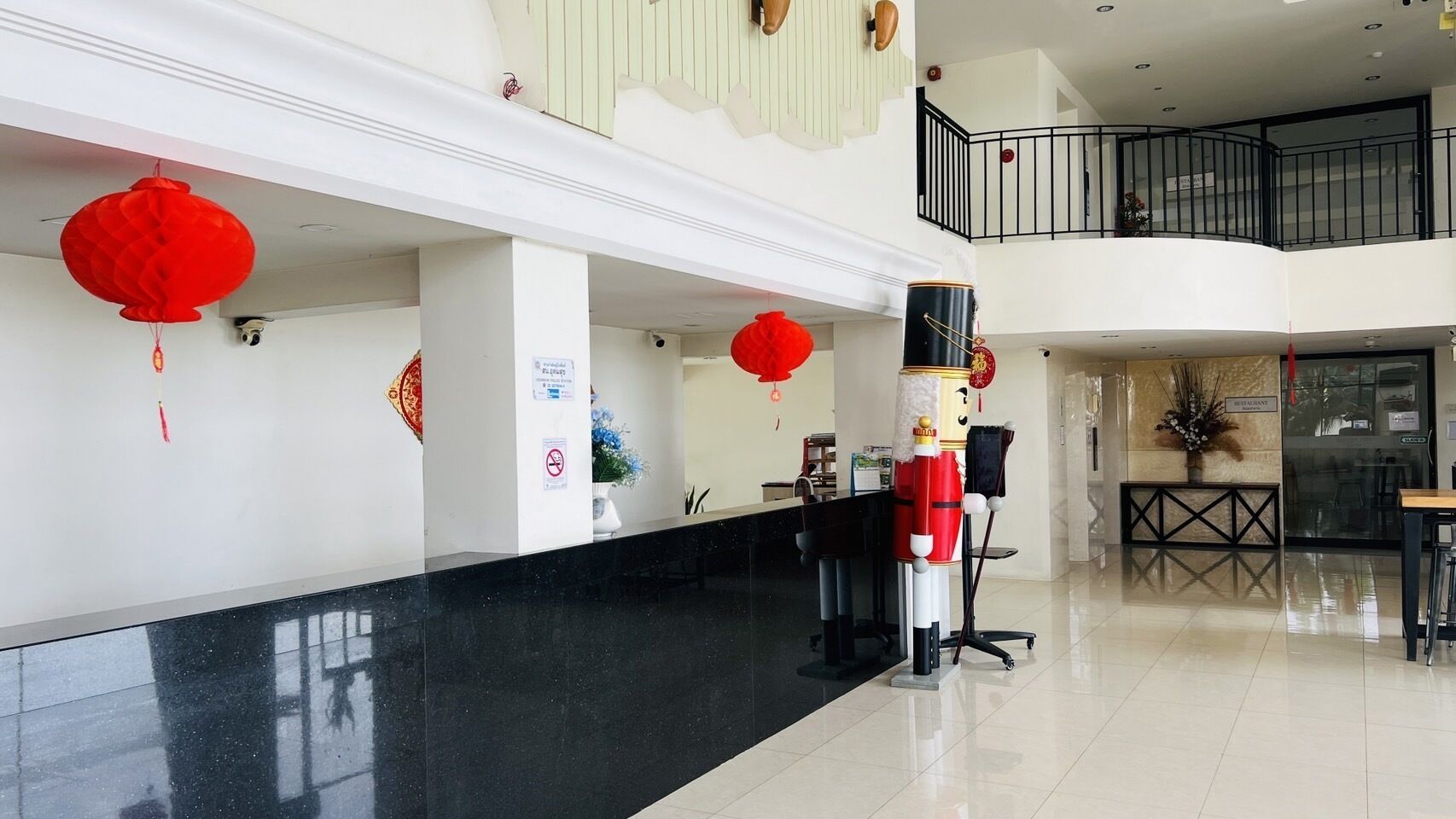 A hotel lobby with a black marble reception desk, red lanterns, and a decorative column.