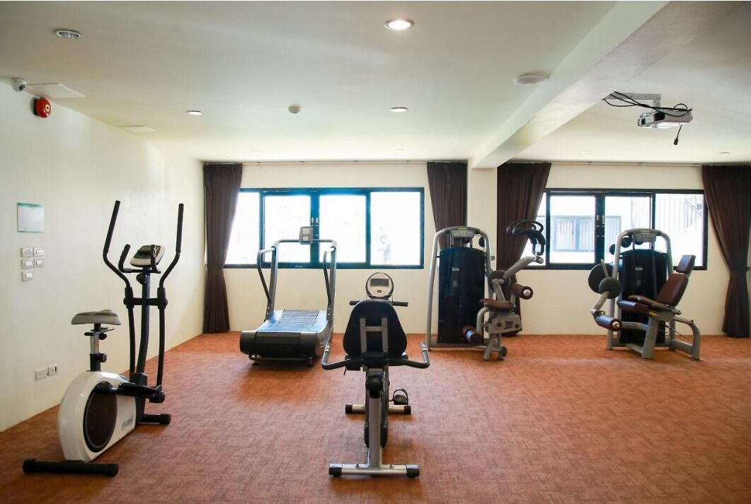 Une salle de sport équipée de machines de cardio, de matériel d’entraînement en force et dotée de grandes fenêtres.