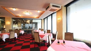 Ein Restaurant mit Tischen, die mit rot-weißen Tischdecken bedeckt sind, in einem geräumigen Zimmer mit kariertem Boden.