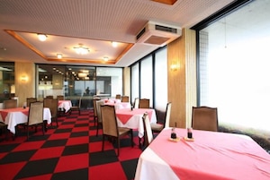 Un restaurante con mesas cubiertas por manteles rojos y blancos, dispuesto en un espacio amplio con suelo a cuadros.