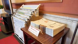 Ein Holztisch mit einer Zeitungsauslage und einem Schild in japanischer Schrift.