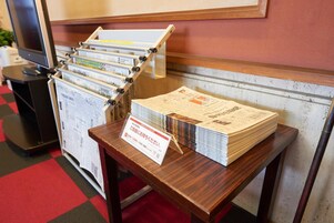 Una mesa de madera con una pila de periódicos y un letrero en japonés.