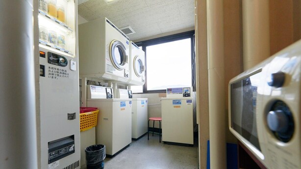 A laundry room with washing machines, dryers, and a small seating area. - Hotel Select Inn Tsuruga (Tsuruga)