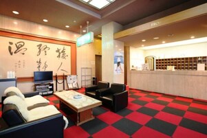 Un vestíbulo de hotel con mostrador de recepción, zona de estar y una gran pared con caligrafía japonesa.