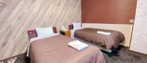 A hotel room with two beds, a wooden accent wall, a brick wall, and a carpeted floor.