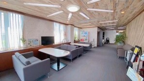A modern interior with a long table and sofas, a television, and a brick wall. - Hotel Select Inn Tsuyama (Tsuyama)