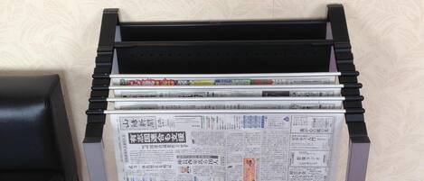 A newspaper stand with multiple newspapers stacked on top of each other.