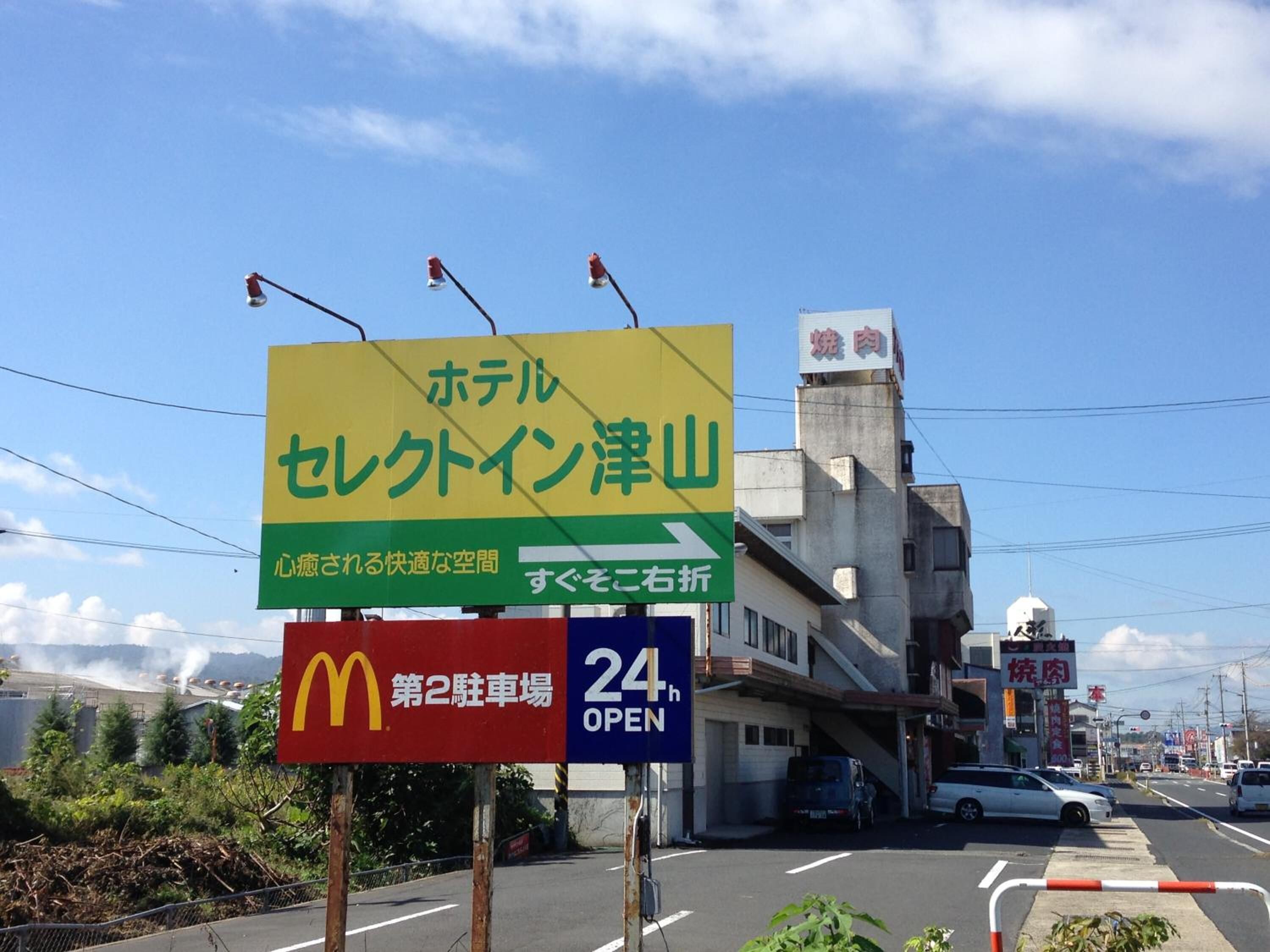 Un letrero de hotel con texto en japonés, un letrero de McDonald's y un letrero que indica 'abierto las 24 horas'.