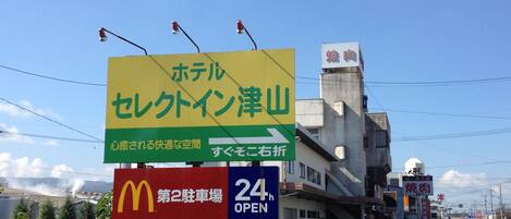 Un letrero de hotel con texto en japonés, un letrero de McDonald's y un letrero que indica 'abierto las 24 horas'.