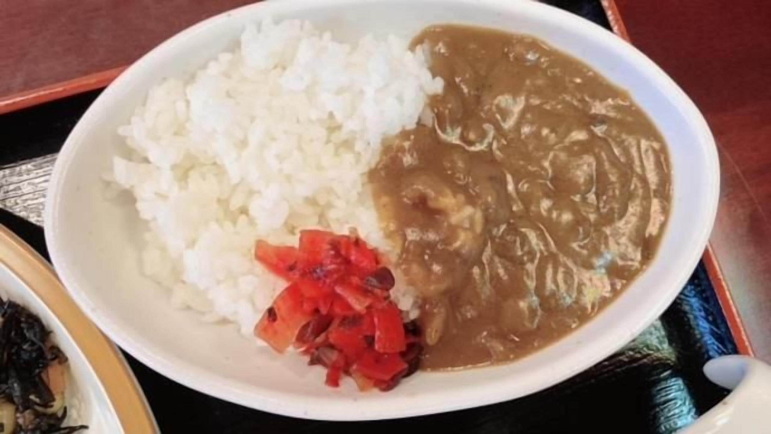 Un plato con arroz blanco, salsa marrón y pimientos rojos.