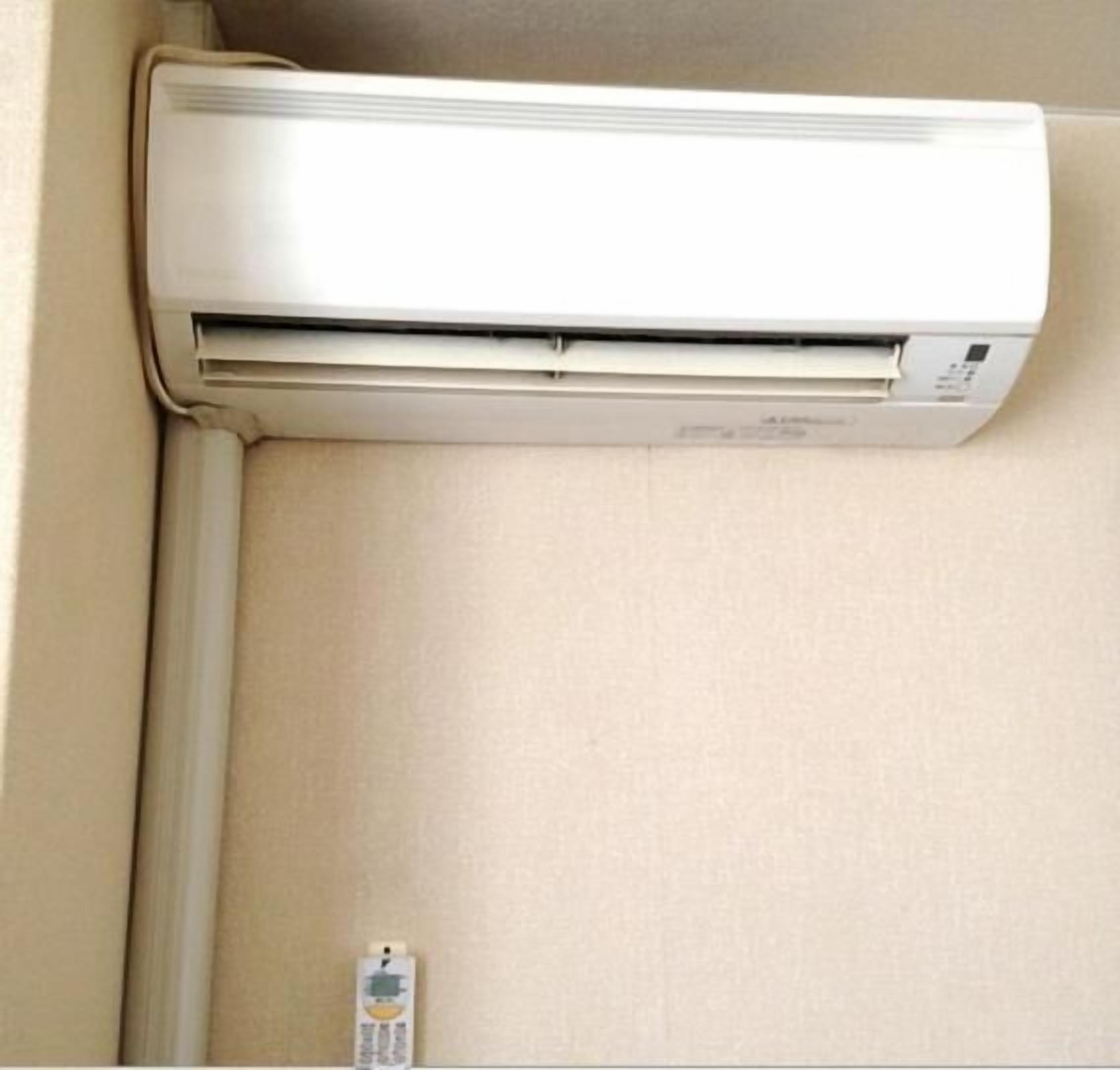 A white air conditioning unit mounted on a beige wall.