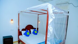Uma cama com dossel, uma mesinha de cabeceira e um ar condicionado fixado na parede.