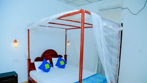 Uma cama de dossel com cortina, paredes brancas e uma pequena mesa de cabeceira.