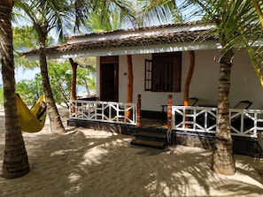A beach house with a tiled roof, a porch with white railings, and a hammock. - Ibisbird Beach Bungalows, Sport, Spa and Restaurant (Tangalle)