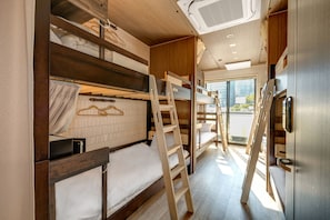 A compact, well-lit room with bunk beds, a wooden ladder, and a sliding door leading to an outdoor area.