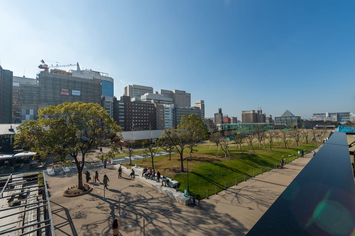 Un paisaje urbano con edificios modernos, un parque con árboles y un largo sendero.