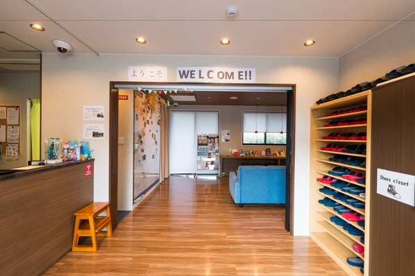 A reception area with a wooden bench, a shoe closet, and a blue couch.