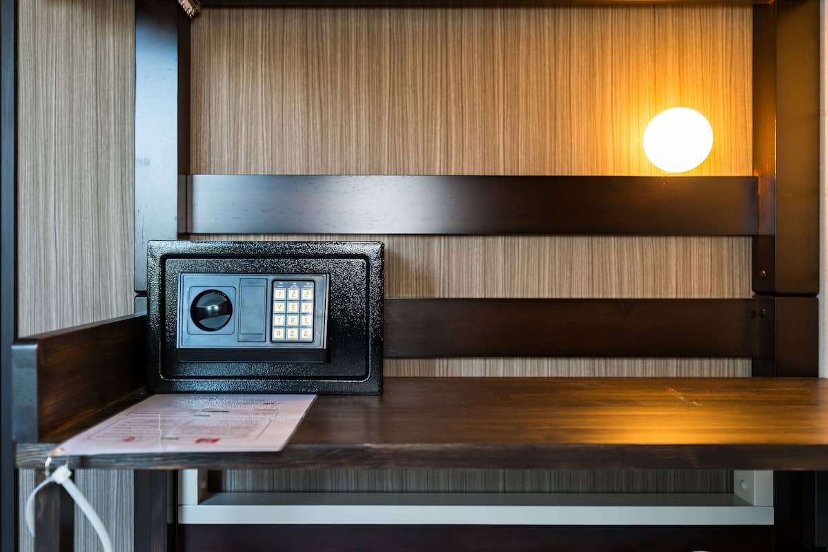 Una habitación con un banco de madera, una caja fuerte y una lámpara fijada a la pared.