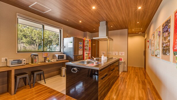 A modern kitchen with wooden flooring, a large island with a sink, and a microwave. - Kintetsu Friendly Hostel Tennojipark Osaka (Osaka)