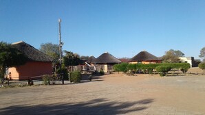 A rural village with thatched-roof houses, a paved road, and a utility pole.