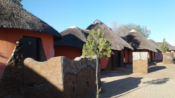 A row of thatched-roof huts with a paved walkway between them.
