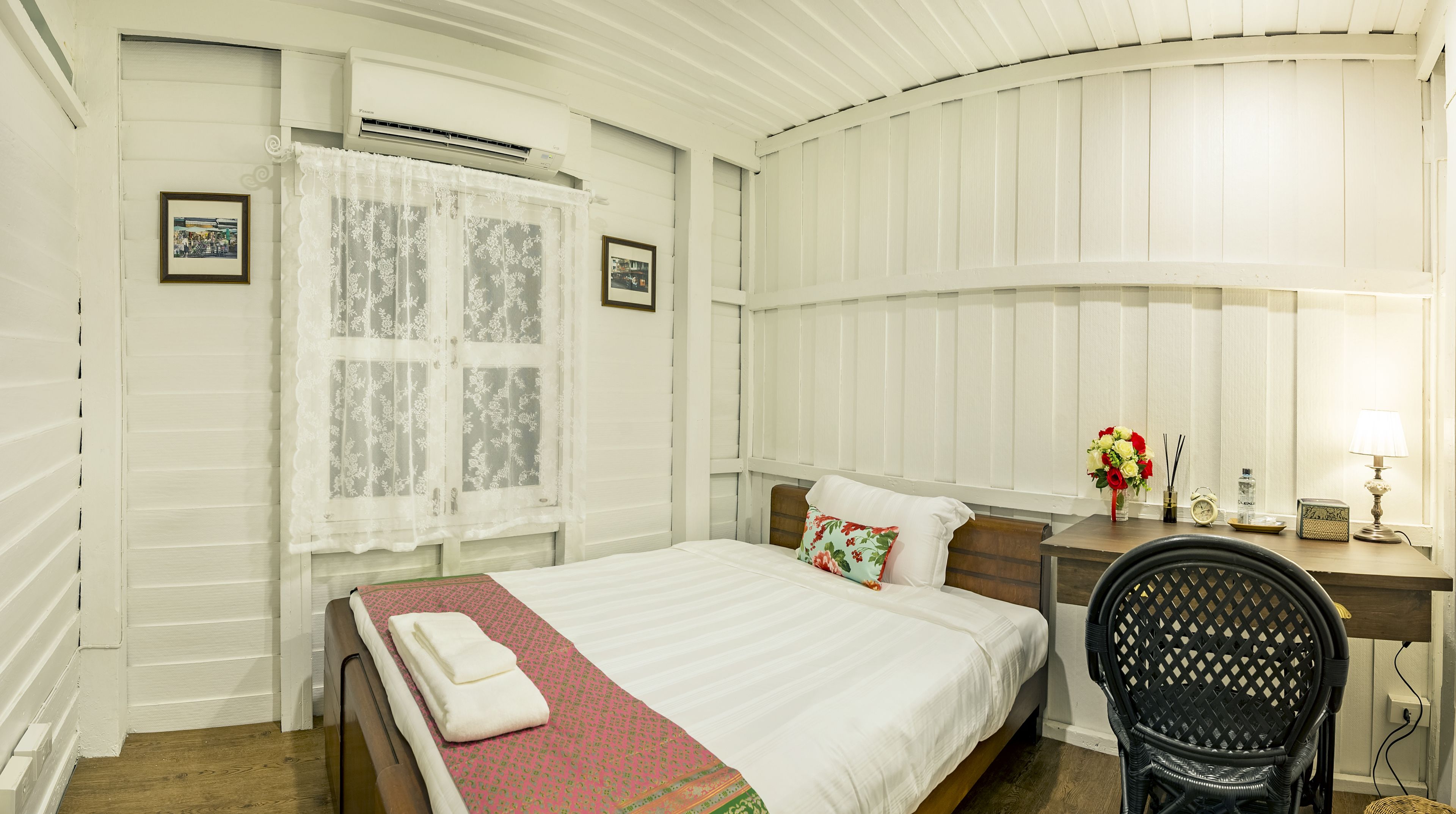 Un dormitorio ordenado con cama, escritorio, silla y ventana con cortinas.