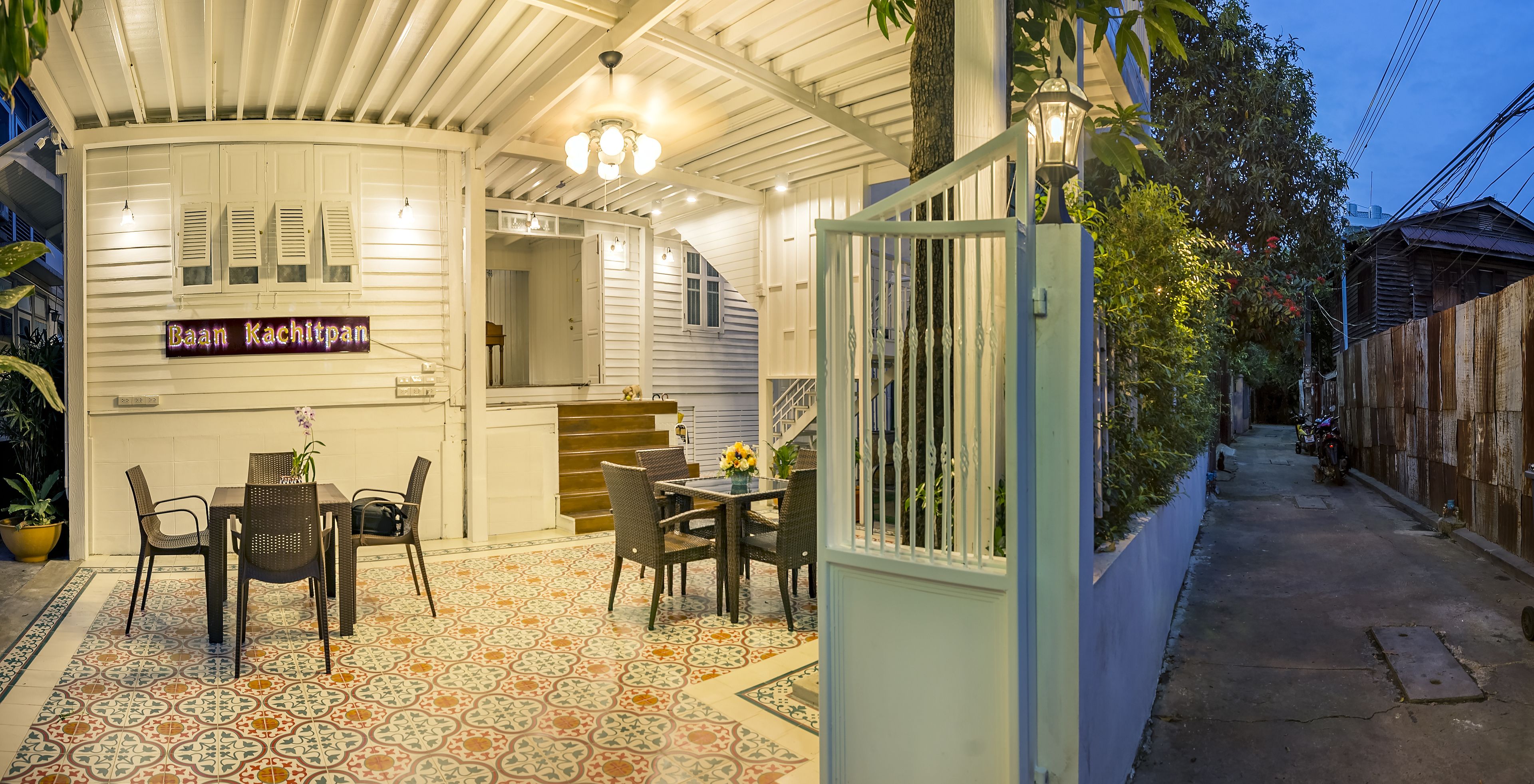 Un área de comedor al aire libre techada con una mesa, sillas, una escalera y un letrero que dice "Daan Kachitpan".