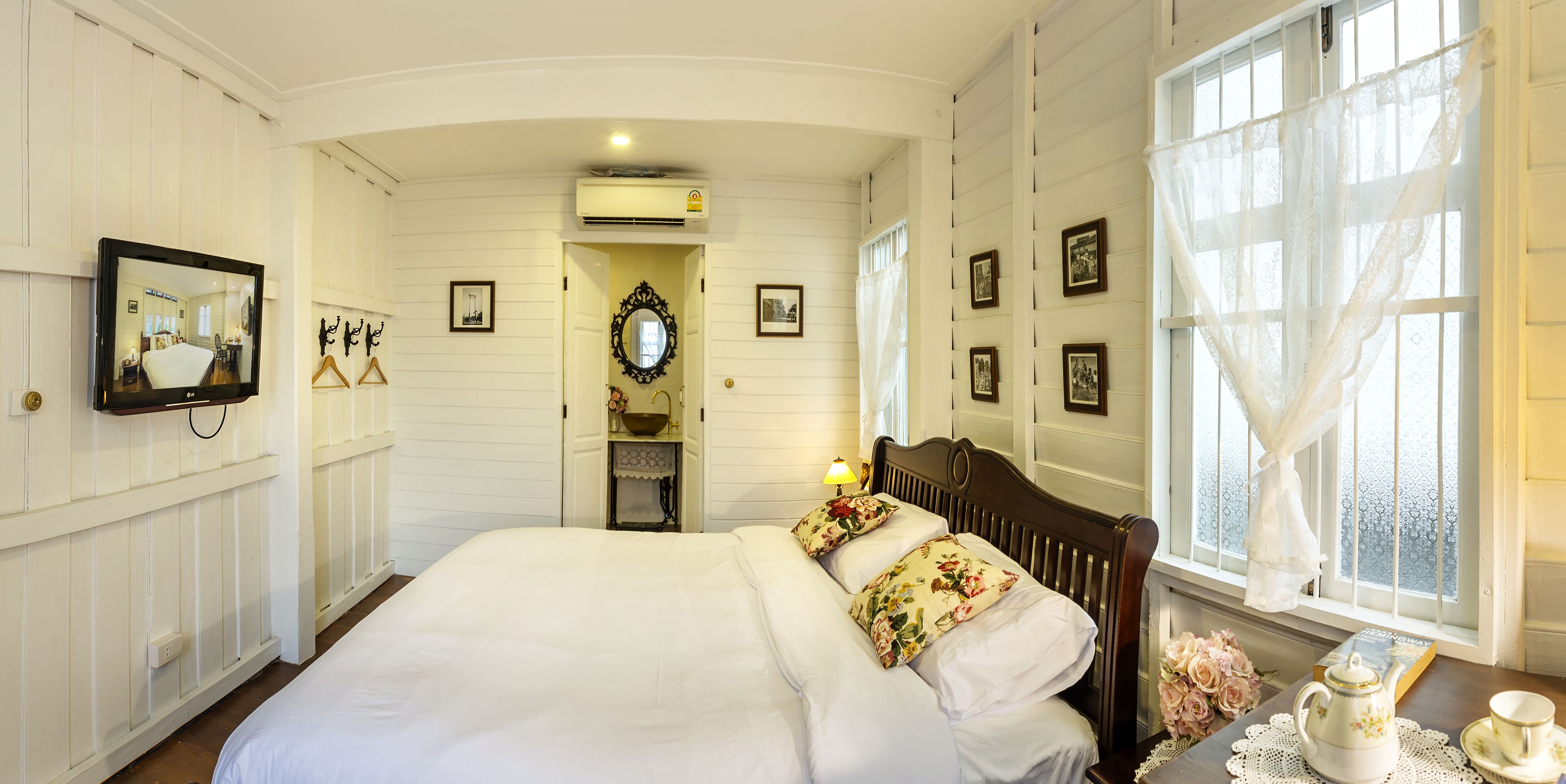 Un dormitorio con una cama grande, un espejo, un tocador con lavabo y una ventana con cortinas.