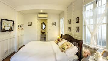 Un dormitorio con una cama grande, un espejo, un tocador con lavabo y una ventana con cortinas.