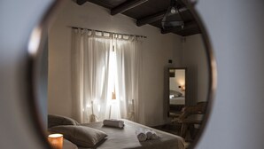 Een slaapkamer met een bed, gordijnen, een spiegel en een lamp.