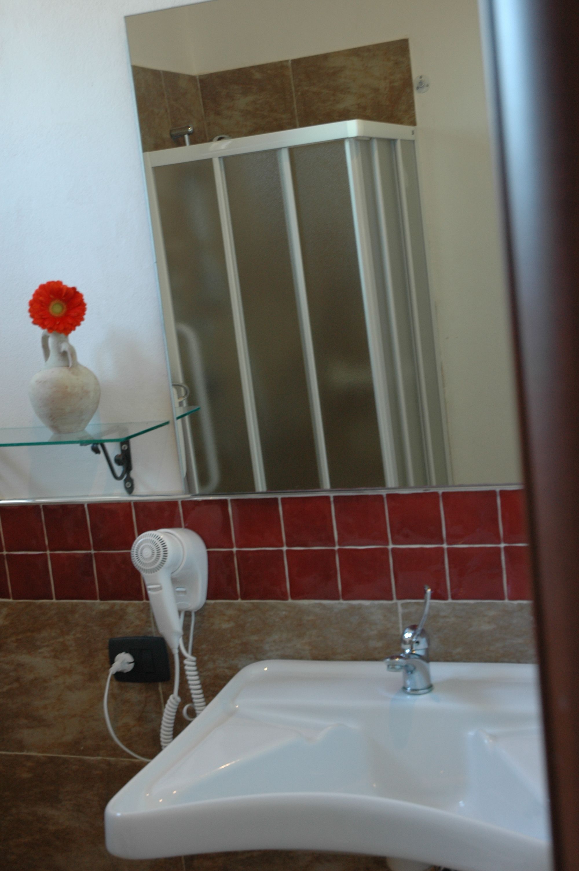 A bathroom with a white sink, a hairdryer, and a mirror above the sink.