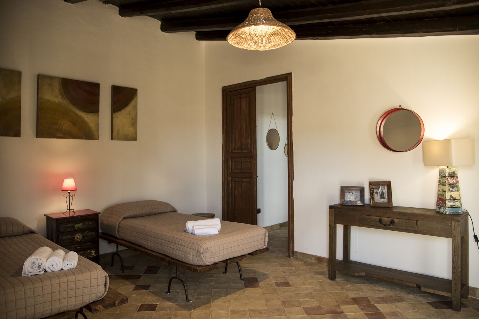 A bedroom with a bed, bedside tables, a dresser, a mirror, and artwork on the walls.