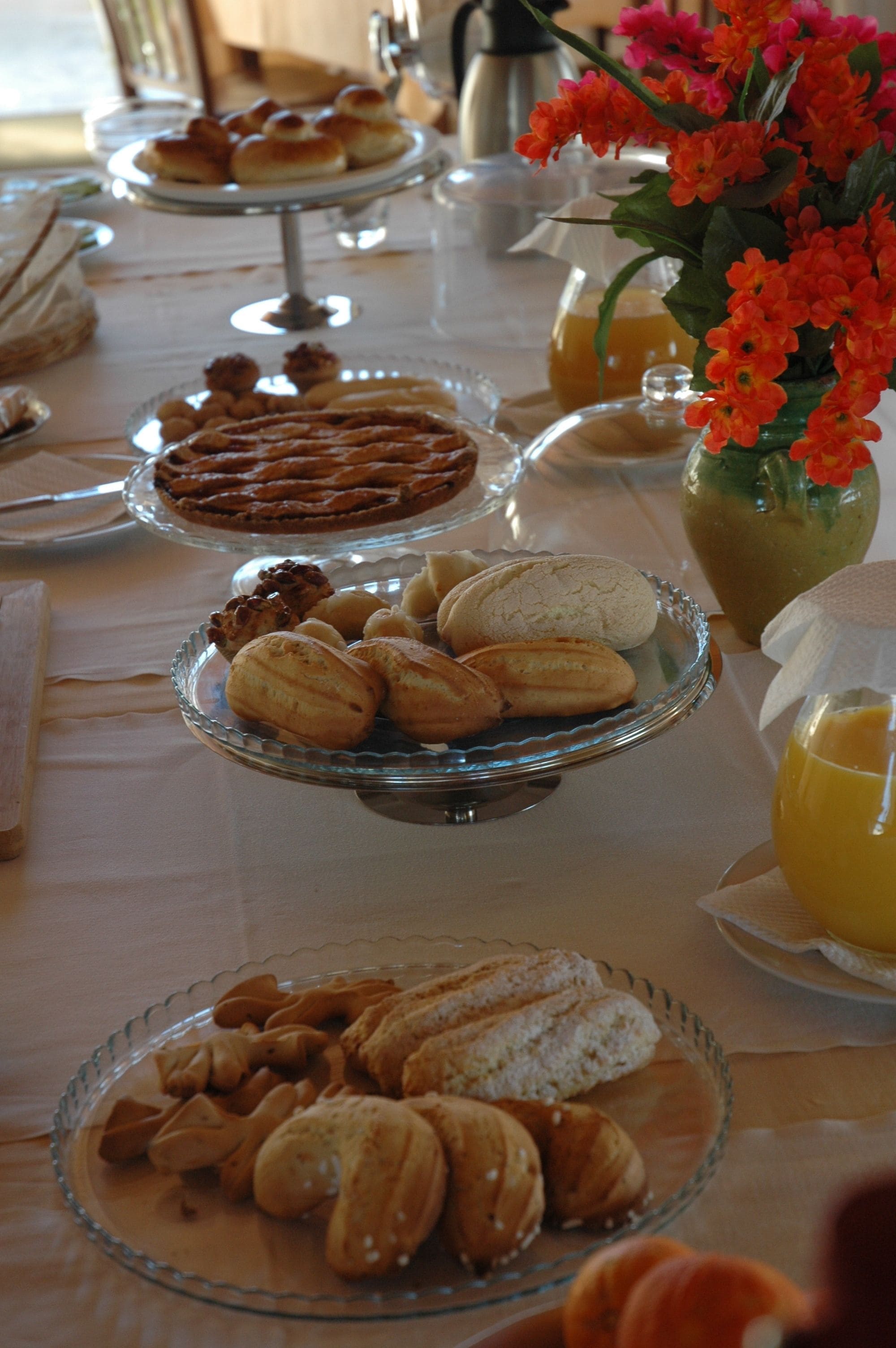 A buffet table with various pastries and a vase of flowers.