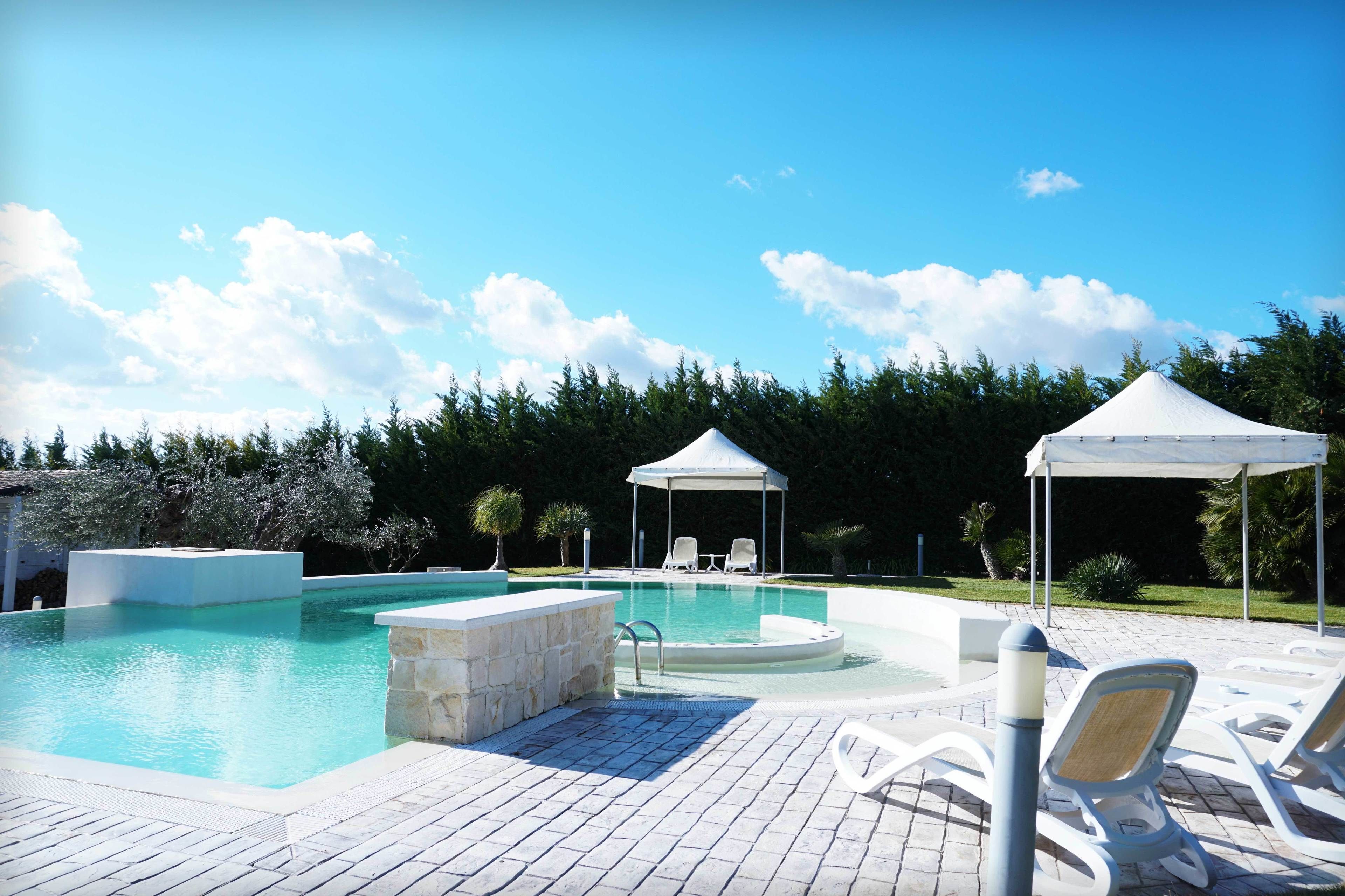 Ein Swimmingpool mit Liegestühlen und einer Laube.
