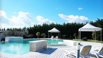 Ein Swimmingpool mit Liegestühlen und einer Laube.