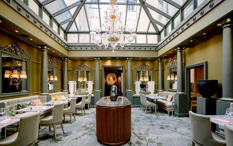 A luxurious dining area with a central bar, high ceilings, and ornate chandeliers.